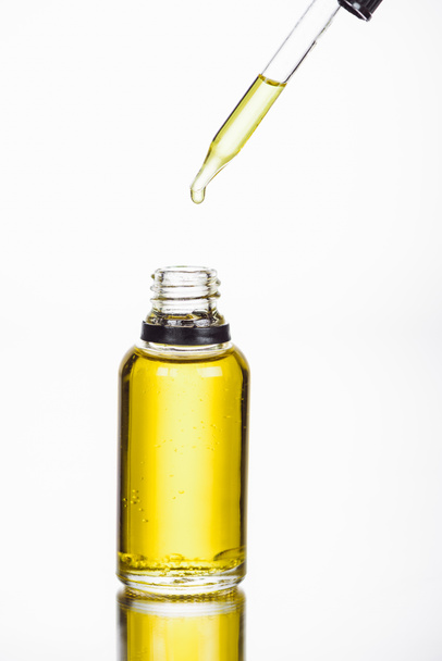kroplomierz w pobliżu butelki z naturalnym serum izolowane na białym - Zdjęcie, obraz