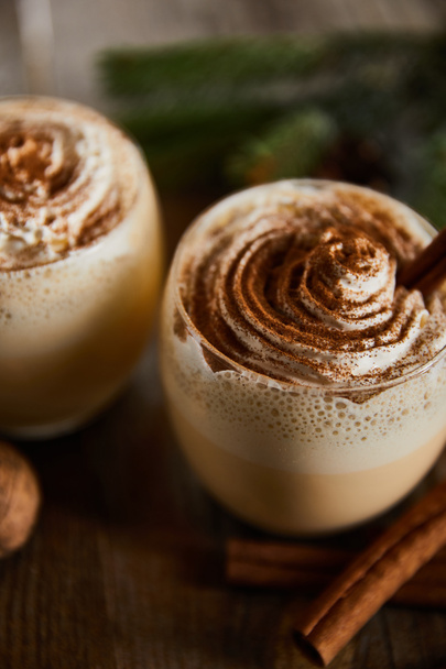 close up view of tasty eggnog drink with whipped cream and cinnamon on wooden table - Photo, Image