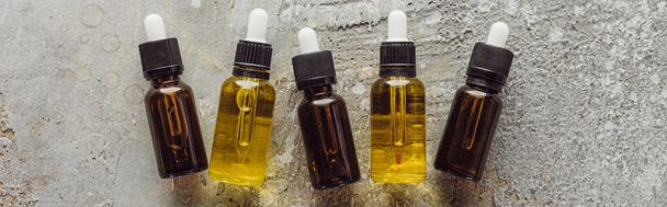 panoramic shot of bottles with natural serum near fir branches on grey stone surface - Photo, Image