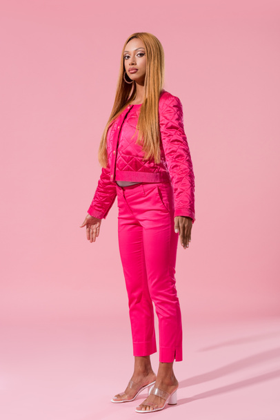 attractive, trendy african american woman standing on pink background, fashion doll concept - Photo, Image