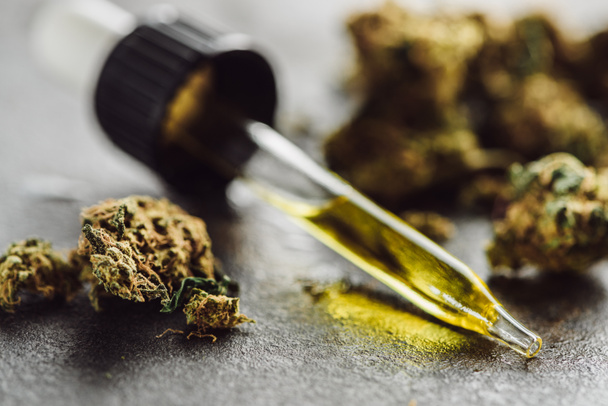 close up view of medical marijuana buds and dropper with hemp oil on stone surface - 写真・画像