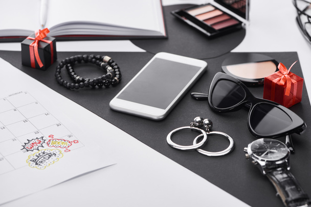 selective focus of calendar, eye shadow, gifts, smartphone, earrings, bracelets, wristwatch and face powder  - Photo, Image