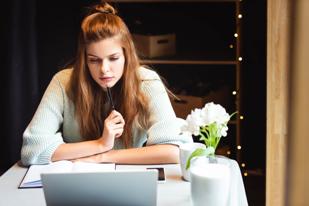 zamyślona kobieta studiuje online z laptopem w kawiarni - Zdjęcie, obraz