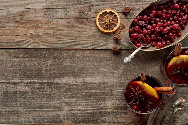 ylhäältä näkymä punaisesta maustetusta glögiviinistä marjoilla, aniksella, appelsiiniviipaleilla ja kanelilla puisella maalaispöydällä
 - Valokuva, kuva