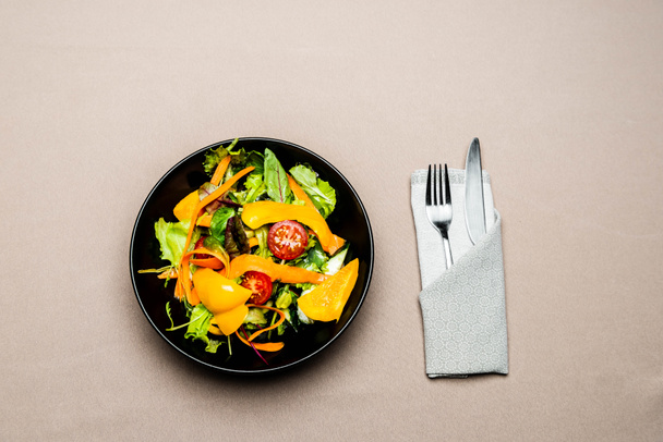  πάνω όψη της σαλάτας σε πιάτο με πιρούνι και μαχαίρι στο τραπέζι - Φωτογραφία, εικόνα