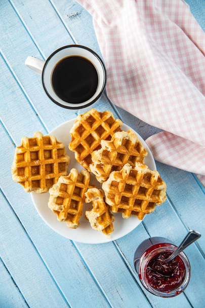 Tasty sweet waffles with raspberry jam and tea cup. - Photo, Image