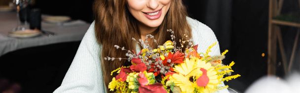 cropped view of happy woman with bouquet of autumn flowers in cafe - Foto, Imagem