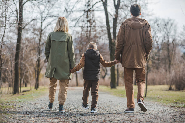 jovem bela família andando de mãos dadas pelo parque da cidade
 - Foto, Imagem