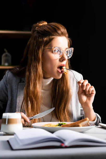 attractive redhead woman eating breakfast in cafe with notepad   - Fotó, kép