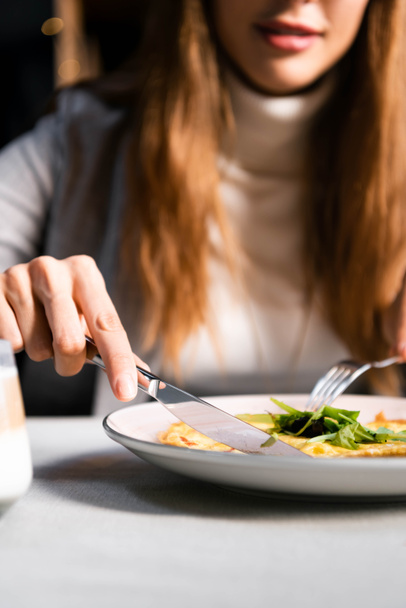 cropped view of woman eating omelet for breakfast in cafe  - Foto, Bild