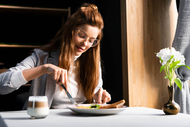 beautiful redhead woman eating breakfast with coffee in cafe with flowers - Zdjęcie, obraz
