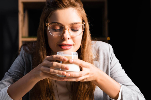 attractive woman in eyeglasses holding glass of coffee with closed eyes in cafe  - Foto, imagen