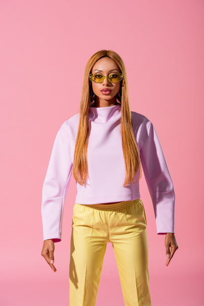 widok z przodu stylowe, blondynka Afroamerykanka stoi odizolowany na różowy, koncepcja lalka moda - Zdjęcie, obraz