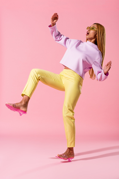 stijlvol Afrikaans amerikaans vrouw stappen op roze achtergrond, mode pop concept - Foto, afbeelding