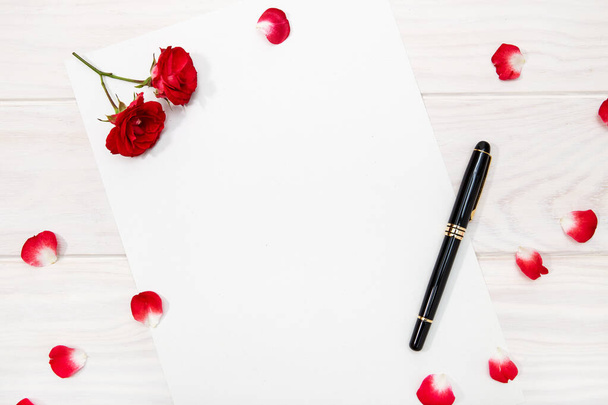 Lettera d'amore con rosa rossa e petali sul tavolo di legno bianco. Scherza. Copia spazio
 - Foto, immagini