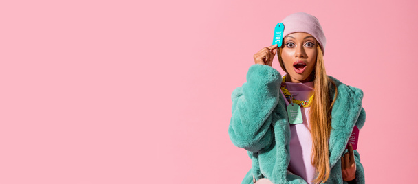 plano panorámico de emocionado, mujer afroamericana de moda tocando la etiqueta con la inscripción de venta aislado en rosa, concepto de muñeca de moda
 - Foto, Imagen