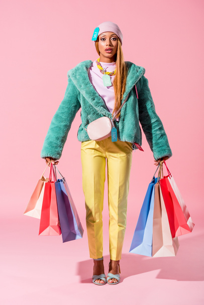 Pembe arka planda alışveriş torbaları taşıyan Afro-Amerikan kadın, moda bebeği konsepti - Fotoğraf, Görsel