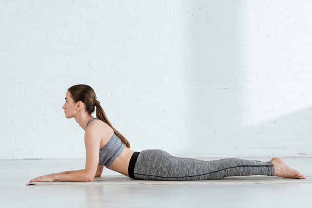 side view of young woman in sportswear practicing yoga in sphinx pose - Photo, Image