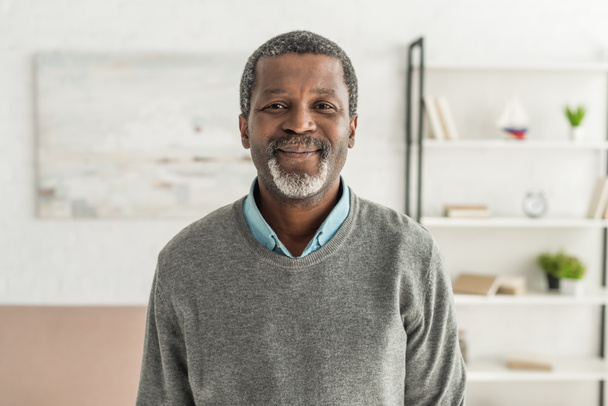 vidám afro-amerikai férfi szürke pulóverben mosolyog a kamerába  - Fotó, kép