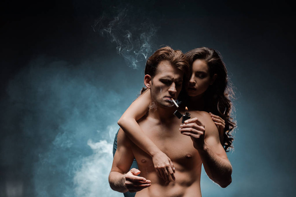 sexy woman hugging man smoking cigarette in dark room with smoke - Photo, Image