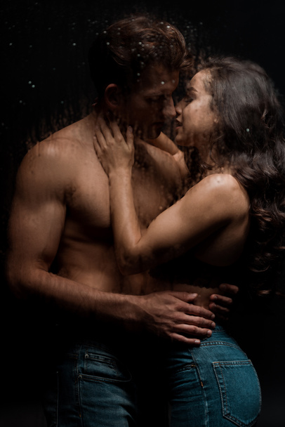 beautiful passionate couple hugging and kissing behind wet glass - Photo, Image