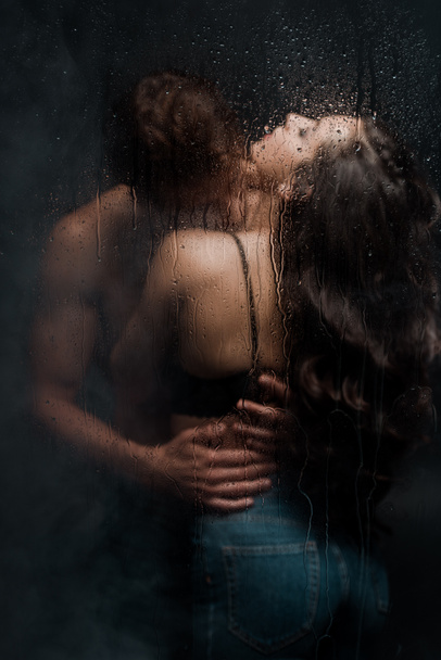 σέξι ζευγάρι αγκαλιάζει και φιλιά πίσω από υγρό γυαλί - Φωτογραφία, εικόνα