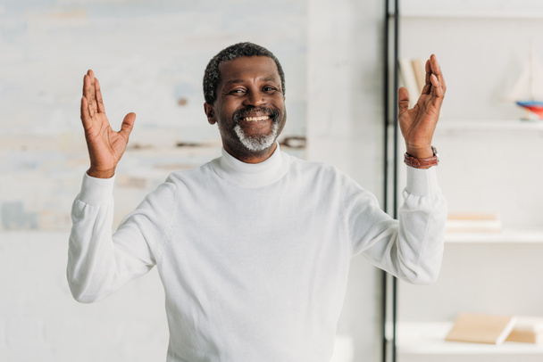  happy african american man showing wow gesture and smiling at camera - Foto, Imagen