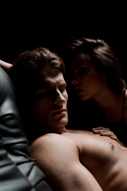beautiful seductive couple sitting on sofa in dark room - Fotografie, Obrázek