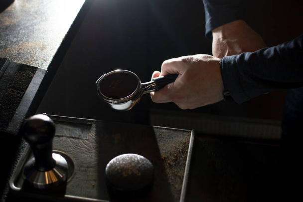 Prozess der Kaffeezubereitung, der Barista presst gemahlene Bohnen, der Kerl kocht Kaffee in einem Café - Foto, Bild
