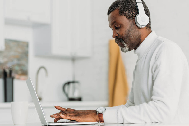 homem americano africano concentrado em fones de ouvido digitando no laptop
 - Foto, Imagem