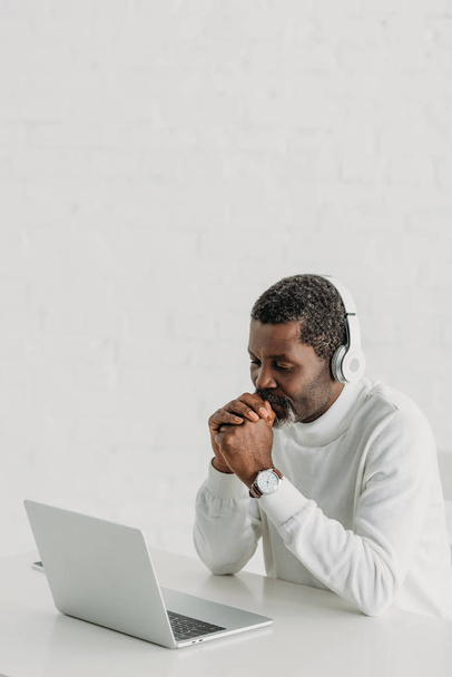 serious african american man in headphones sitting near laptop - Fotó, kép