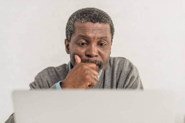 selective focus of thoughtful african american man sitting near laptop - Foto, immagini