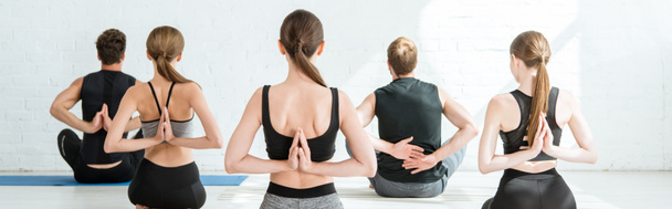 Rückansicht von meditierenden jungen Männern und Frauen in Blitz-Pose mit gebeteten Händen hinter dem Rücken, Panoramaaufnahme - Foto, Bild