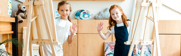 plano panorámico de niños felices saludando las manos en la escuela de arte
  - Foto, imagen