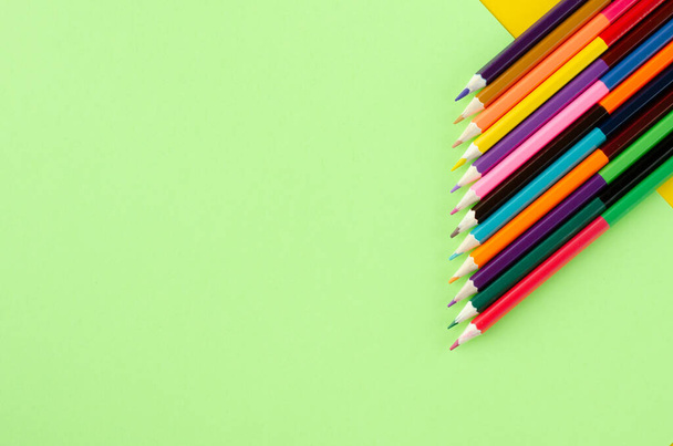 Colored pencils composition on yellow and green background. - Фото, изображение