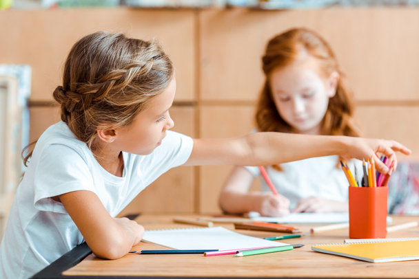 selective focus of kid taking color pencil near redhead child  - Zdjęcie, obraz