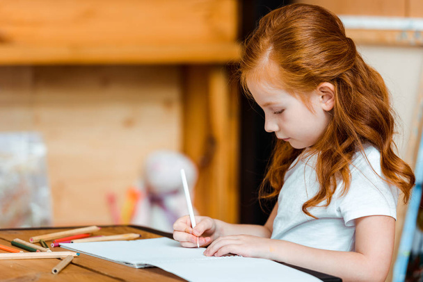 cute redhead kid drawing on paper in art school  - Foto, Bild
