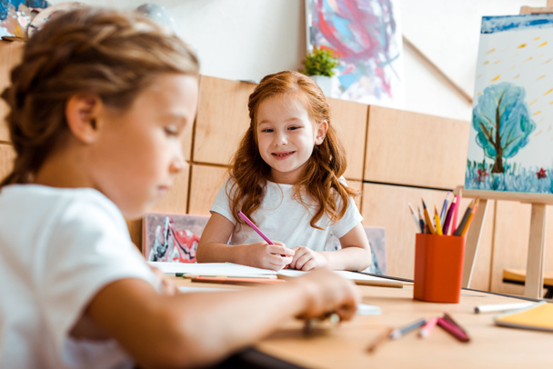 selektywne skupienie szczęśliwego rudego dziecka z kolorem ołówka patrzącego na dziecko  - Zdjęcie, obraz