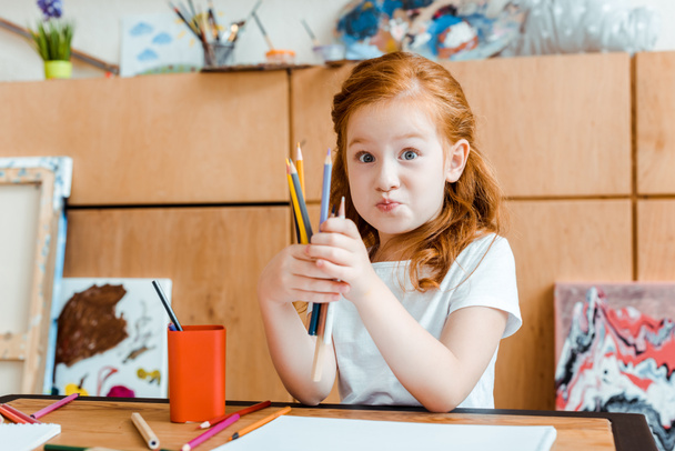 schattig roodharige kind met kleurpotloden in kunst school - Foto, afbeelding