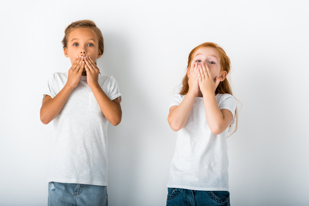 roztomilé děti stojící a zakrývající tváře na bílém  - Fotografie, Obrázek