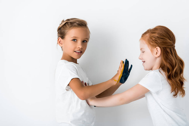 glückliche Kinder mit Farbe auf den Händen, die auf Weiß spielen  - Foto, Bild