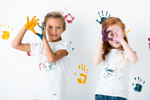 χαρούμενα παιδιά δείχνουν σε σχήμα καρδιάς σημάδι με τα χέρια σε πολύχρωμο χρώμα σε λευκό  - Φωτογραφία, εικόνα