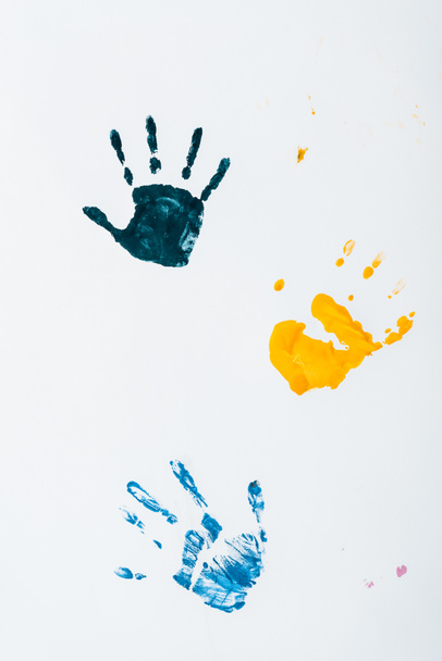 yellow, light blue and dark blue hand prints on white  - Foto, afbeelding