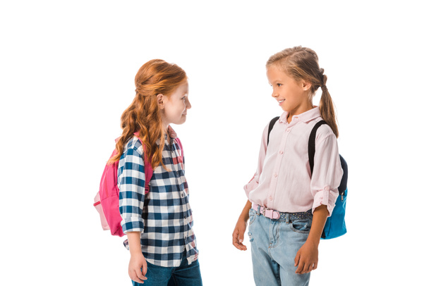 happy schoolkids with backpacks looking at each other isolated on white  - Photo, image