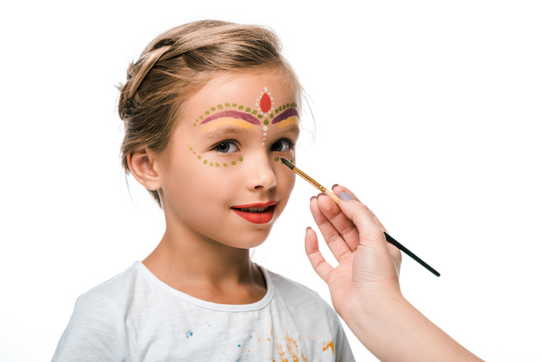 cropped view of woman holding paintbrush near happy kid with face painting isolated on white  - Foto, Imagen