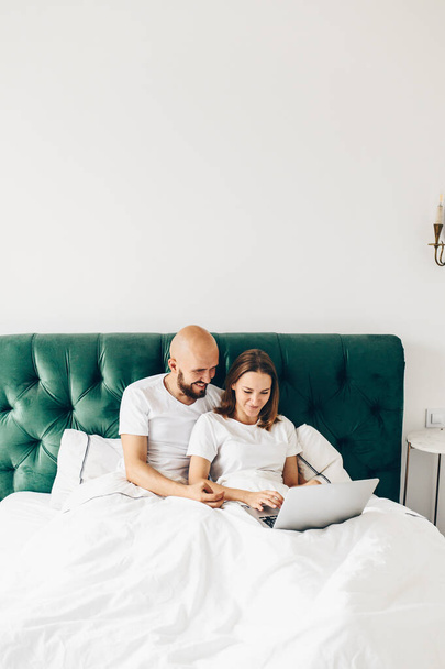 joven pareja usando portátil juntos en la cama
  - Foto, imagen