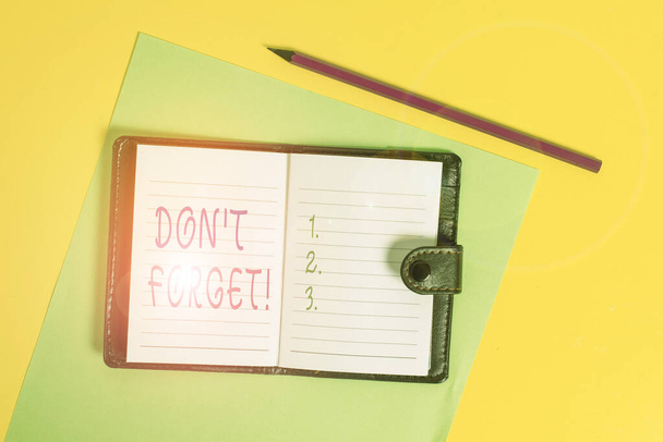Text sign showing Don T Forget. Conceptual photo used to remind someone about important fact or detail Dark leather private locked diary striped sheets marker colored background. - Photo, Image