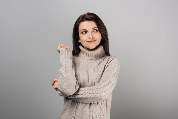 весёлая женщина в свитере смотрит вдаль, изолированная от серых
  - Фото, изображение
