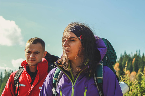 Girl and man hikers in mountains. Travel backpacks and clothing. - Photo, Image