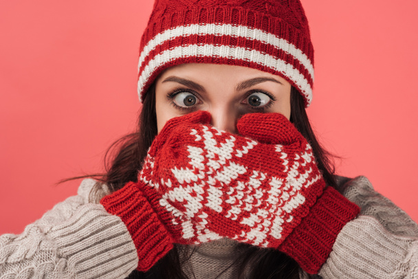 woman in knitted hat covering face with warm gloves isolated on pink  - Photo, Image